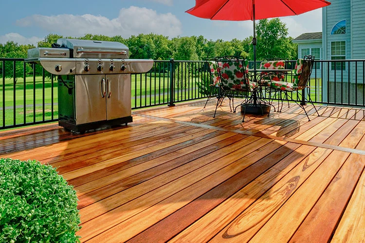 A wooden deck with an umbrella and grill, designed and constructed by a skilled home improvement contractor.