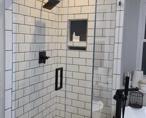 A black and white tiled shower with a glass door, perfect for bathroom remodeling.