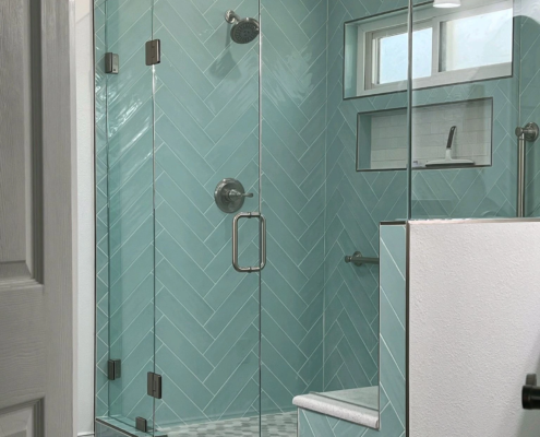 A bathroom with a glass shower door and blue tile, perfect for bathroom remodeling.
