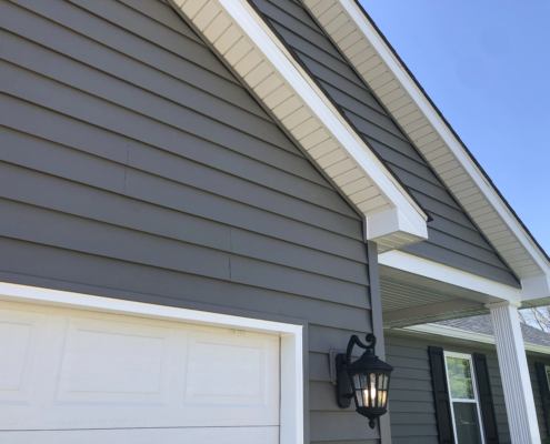 A house with gray siding and a garage door in need of siding replacement.